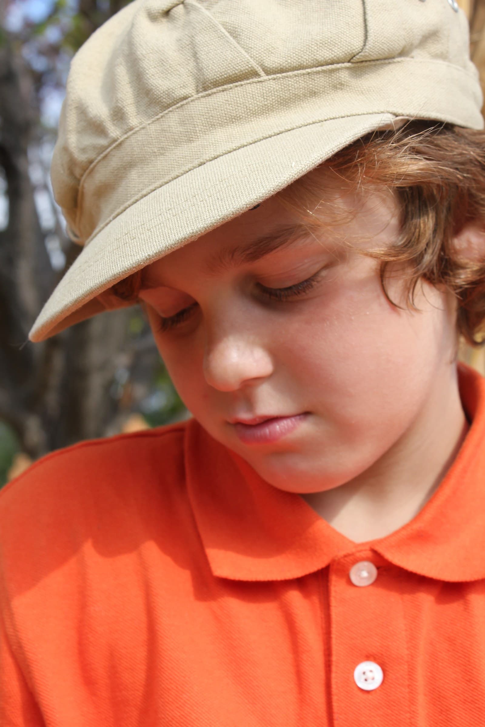 A child in a warm orange shirt photographed in soft natural light