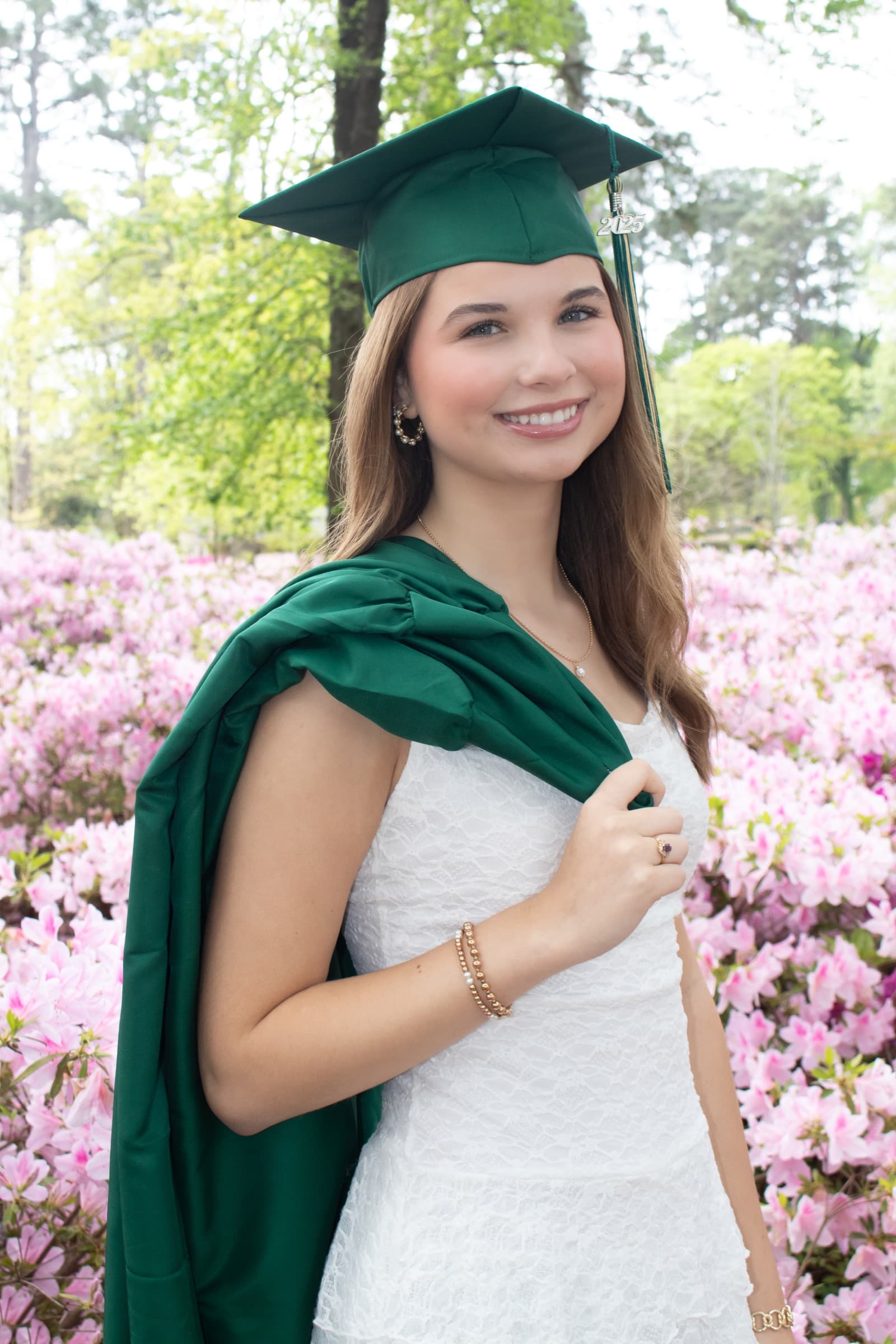 Graduate smiling in a green cap and gown