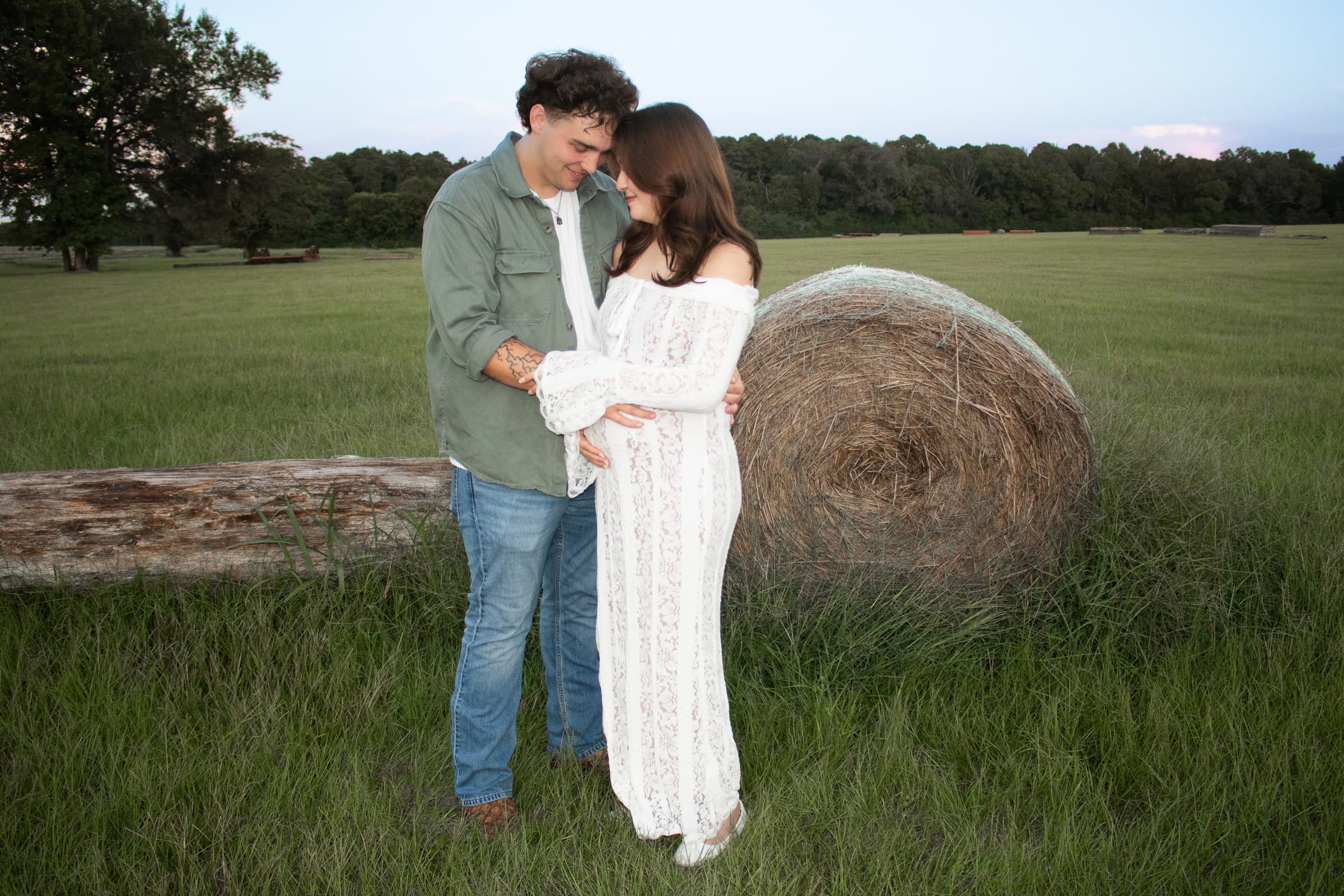 Maternity couple standing together at golden hour
