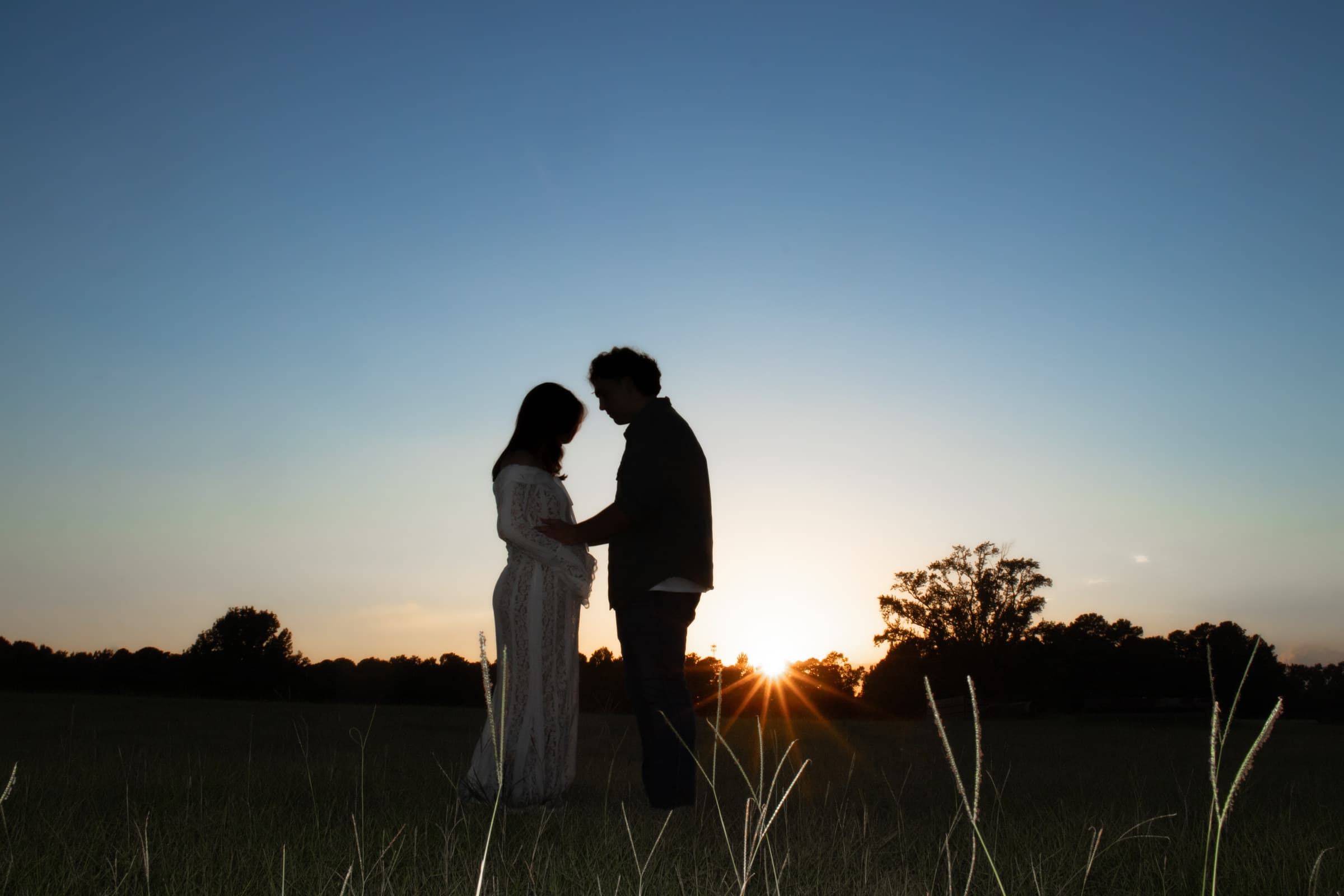 Expecting couple silhouetted together at sunset