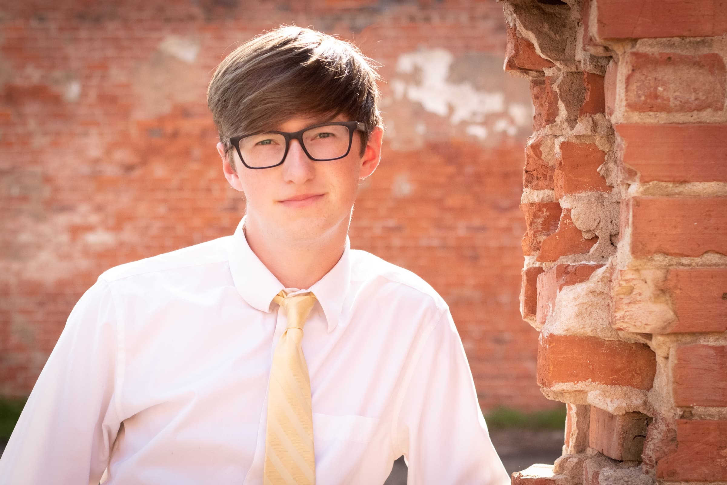 Senior portrait against a warm brick backdrop